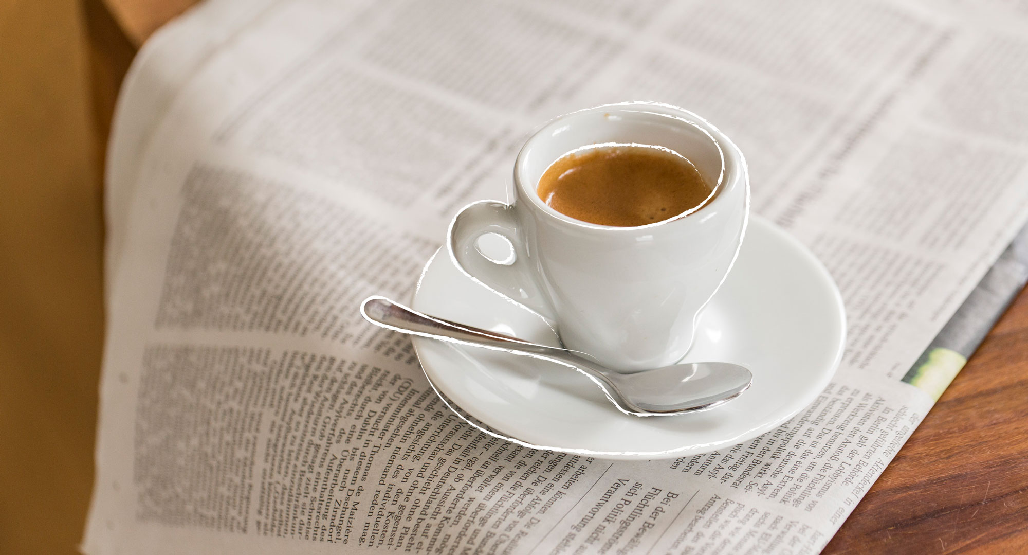 Eine gefüllte Espressotasse steht auf einer Zeitung.